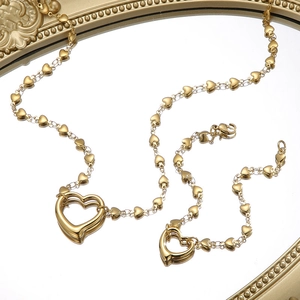 Detailed view of golden heart-shaped necklace and bracelet set with hollow heart pendant