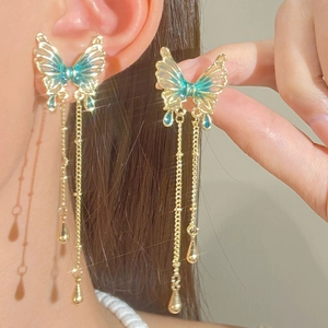 Close-up of elegant gold butterfly earrings with long tassels and crystal details