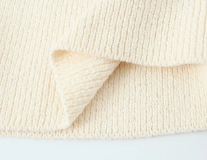 Gros plan sur la texture du tricot crème doux et les détails des motifs tissés verticaux