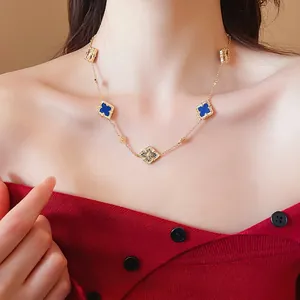 Elegant gold plated clover necklace with blue stones and hollow floral charms on a model