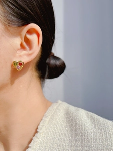 Detailed close-up of heart-shaped earrings with colorful gemstones worn on the ear
