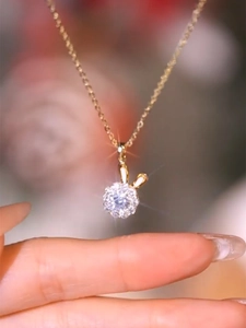 Dettaglio di una collana a coniglio dorata con pietra scintillante tenuta in mano