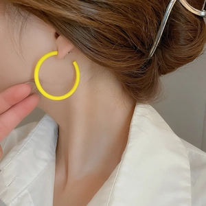 Detail view of oversized bright yellow hoop earrings with a modern matte finish