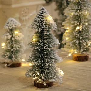 Close-up of a mini snowy pine tree with warm LED lights on a rustic wooden base