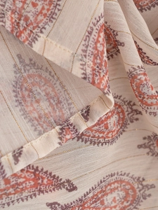 Macro detail of beige paisley printed fabric with fine gold thread and neat stitching
