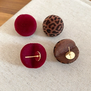 Detailed view of red and leopard print velvet stud earrings with gold metal backing