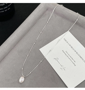 Detailed shot of silver stainless steel satellite chain with baroque pearl pendant