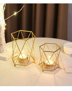 Detail of geometric gold metal candle holders with glass inserts on a cozy dining table