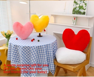 Detail of plush heart cushions in pink, yellow, red and white on a wooden chair