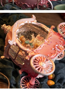 Close-up of pink gold princess carriage music box with swirling glitter and figurines
