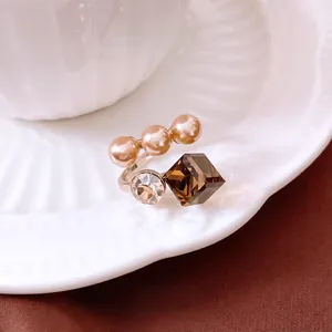 Adjustable silver ring with champagne pearls and brown crystal on a ceramic tray
