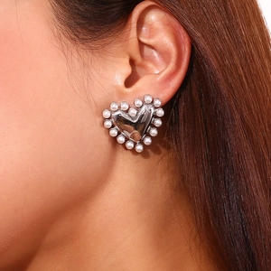 Close-up of elegant silver heart earring with pearl inlay worn by a female model