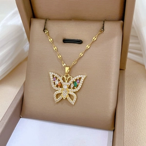Detailed shot of gold butterfly pendant with colorful gemstones in a luxury gift box