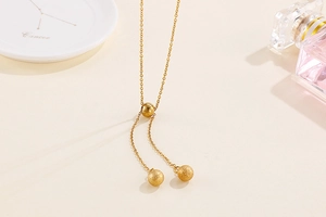 Detailed view of a gold Y-shaped stainless steel necklace with textured ball pendants