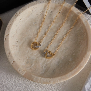 Detail of interlocking gold and silver heart pendants on paperclip chain necklaces