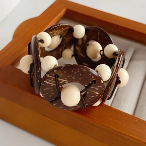 Detailed close-up of dark coconut shell discs and cream beads on elastic bracelet