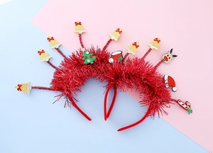 Détail de serre-têtes de Noël rouges avec clochettes dorées et paillettes sur fond coloré