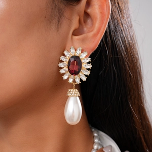 Gros plan de boucles d'oreilles vintage avec pierre rouge rubis et perle blanche