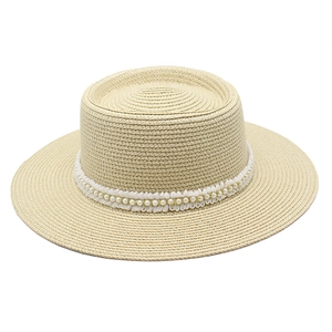 Detail of straw boater hat with delicate white lace trim and embedded pearls