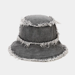 Close-up of distressed edges and frayed fringe detail on dark grey denim bucket hat
