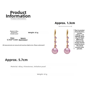 Detail view of gold vintage drop earrings with purple rhinestones and pearl spheres