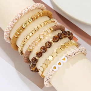 Close-up of stacked polymer clay bracelets with gold beads and marble texture accents