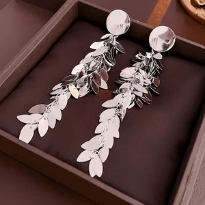 Close-up of silver leaf tassel earrings with metallic sequins in a dark brown display box