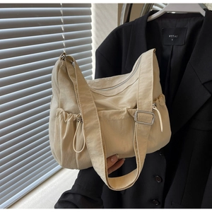 Detail of beige nylon shoulder bag showing wide strap and side drawstring pockets