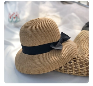 Detailed macro view of woven straw hat featuring a black ribbon bow and fine texture