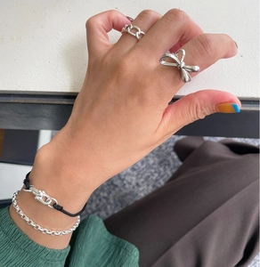 Macro detail of a 925 sterling silver bow ring and chain bracelet on a hand