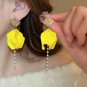 Close-up detail of flower earrings with yellow petals, pearls, and gold tassels