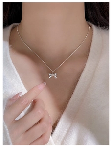 Close-up of s925 silver bow pendant necklace worn on neck with elegant beads