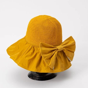 Detail of yellow sun hat featuring knit crown, wide fabric brim and large bow decoration