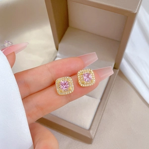 Detailed close-up of a rose gold square pink crystal earring held between fingers