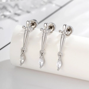Silver dagger stud earrings with cubic zirconia stones displayed on a white stand