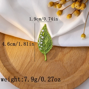 Detailed view of green leaf brooch with pearls showing 4.6cm length and 1.9cm width