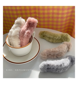 Detail of plush faux fur hair claws in soft pastel colors displayed on a plaid cloth