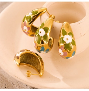 Detailed close-up of gold-plated C-shaped hoop earrings with colorful enamel flower designs