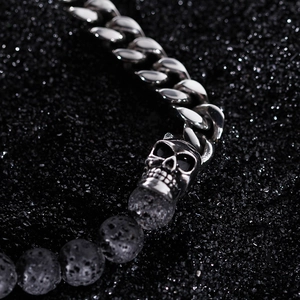 Macro shot of silver skull charm with textured black lava stone beads on a cuban chain