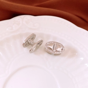 Detailed view of silver oval earrings with sparkling white crystals on a white ceramic tray