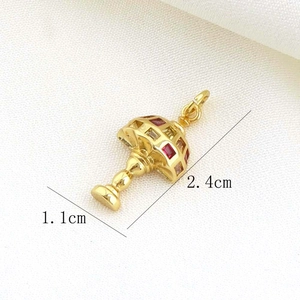Detailed view of a gold umbrella pendant with red gems and dimensions 2.4cm by 1.1cm