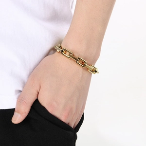 Close-up of industrial gold chain bracelet on wrist showing thick textured metal links
