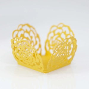 Detail showing yellow laser-cut rose hollow paper cupcake wrappers for wedding decor