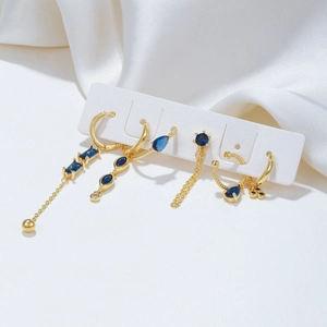 Elegant 5-piece gold earrings set with dark blue zircon stones on white silk fabric