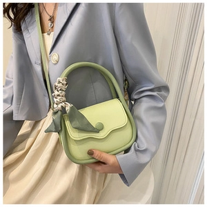 Detail of light green quilted leather bag with floral silk scarf on round top handle