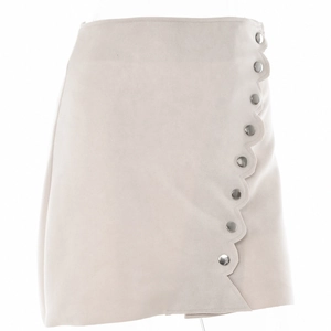 Detail view of beige faux suede mini skirt featuring wavy lace edges and silver buttons
