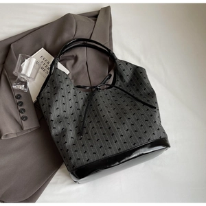 Detailed view of canvas bucket bag with black bow print and leather trim on white background