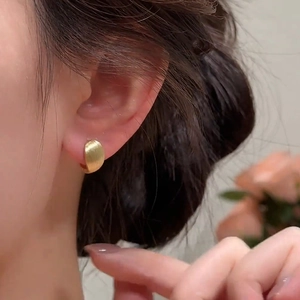 18k gold plated brushed oval hoop earrings worn by a model in a high-quality close-up view