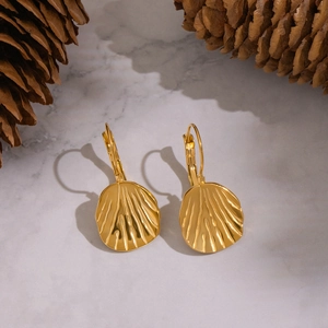 Detailed close-up of golden shell textured round drop earrings on marble background