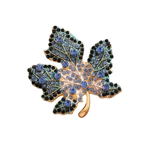 Detail of maple leaf brooch with blue rhinestones and gold alloy texture details
